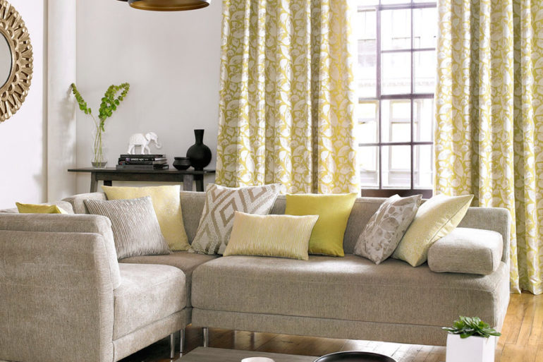salon avec majorité couleur jaune. Table canapé avec fenêtre et rideaux motif